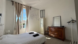 Ein Schlafzimmer mit einem Bett, einem Schminktisch, einem Spiegel und einem Fenster mit Vorhängen.