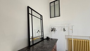 Ein Badezimmer mit Marmorplatte, Holzschrank, Spiegel, Heizkörper und einer Wäscheständer.
