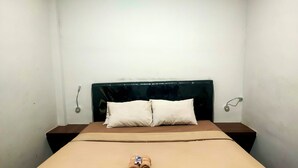 A neatly made bed with a brown bedspread, two pillows, and a rolled towel on the bed. - Nusantara Bypass Mojokerto By Reccoma (Mojokerto)