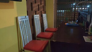 A dining area with a long table, four chairs with red cushions, and a wooden partition. - Nusantara Bypass Mojokerto By Reccoma (Mojokerto)