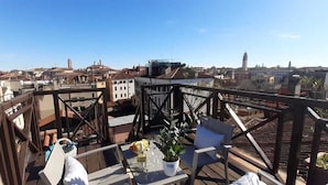 Una terrazza sul tetto con vista sulla città, con un tavolo, sedie e una pianta in vaso.