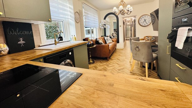 A modern kitchen with a wooden countertop, a black dishwasher, and a welcome sign. - Luxury 2 Bed Designer Flat with Private Garden in London (Bexleyheath)
