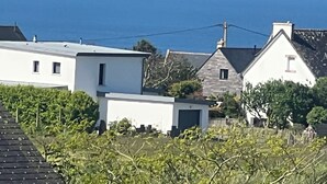 Zona residencial costera con casas, vista despejada del mar y un pequeño edificio en primer plano.