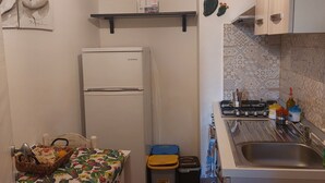 A compact kitchen with a refrigerator, a sink, and a stove. There are decorative plates on the wall and a cactus decoration. - Gamez Floor Apartment 67 (Agrigento)