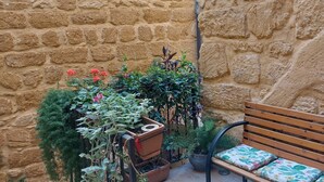 A stone-walled courtyard with a wooden bench and potted plants. - Gamez Floor Apartment 67 (Agrigento)