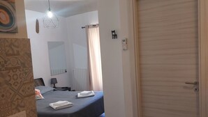 Een hotelkamer met een bed, een bureau, een stoel, een kledingkast, een badkamer en een douche.
