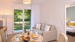 A modern hotel room with a dining area, a sofa, and a bed.