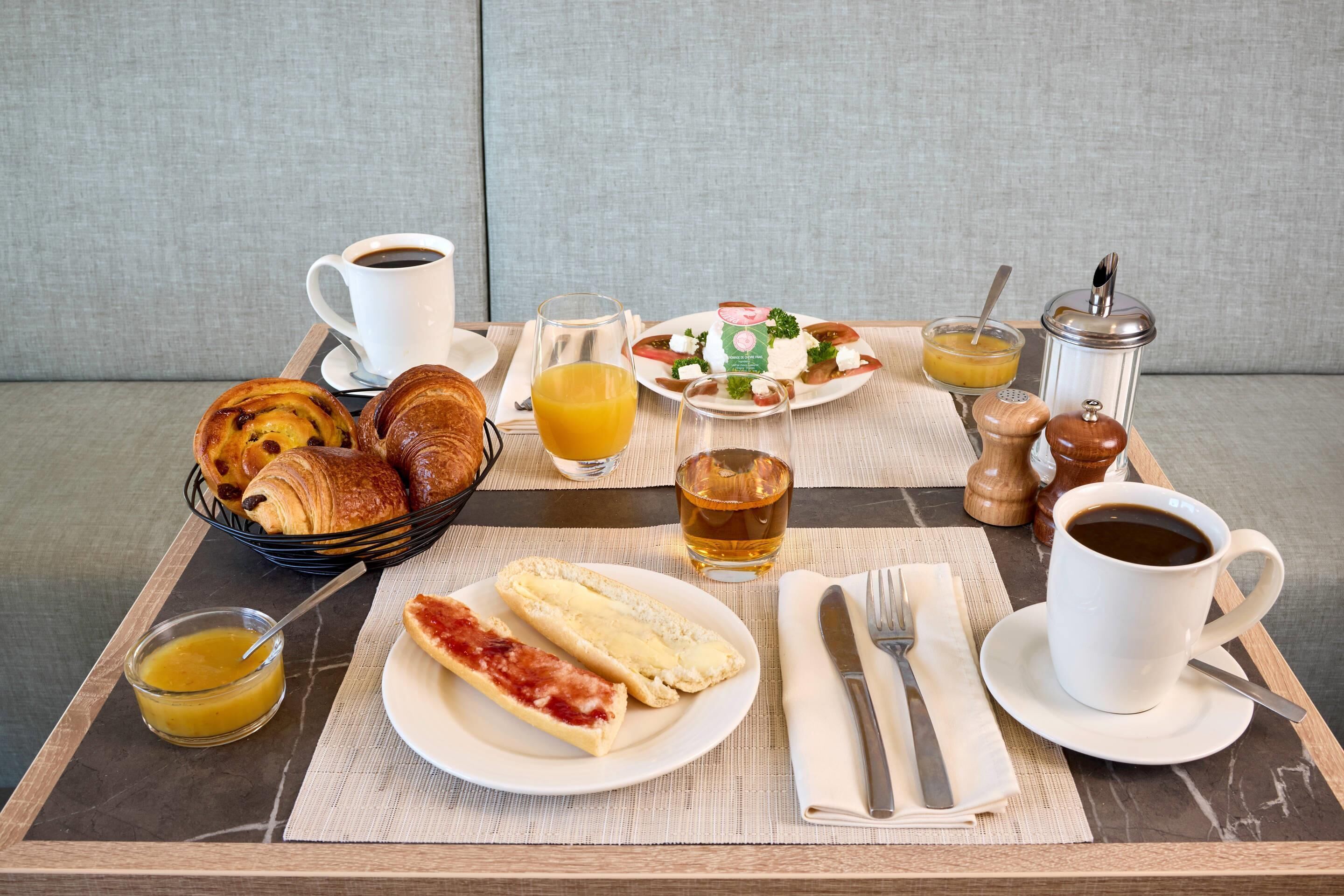 Een ontbijfwagen met croissants, een bord kaas, jam en een glas sinaasappelsap.