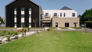 A modern building with a large black facade and a smaller white building with a stone base.