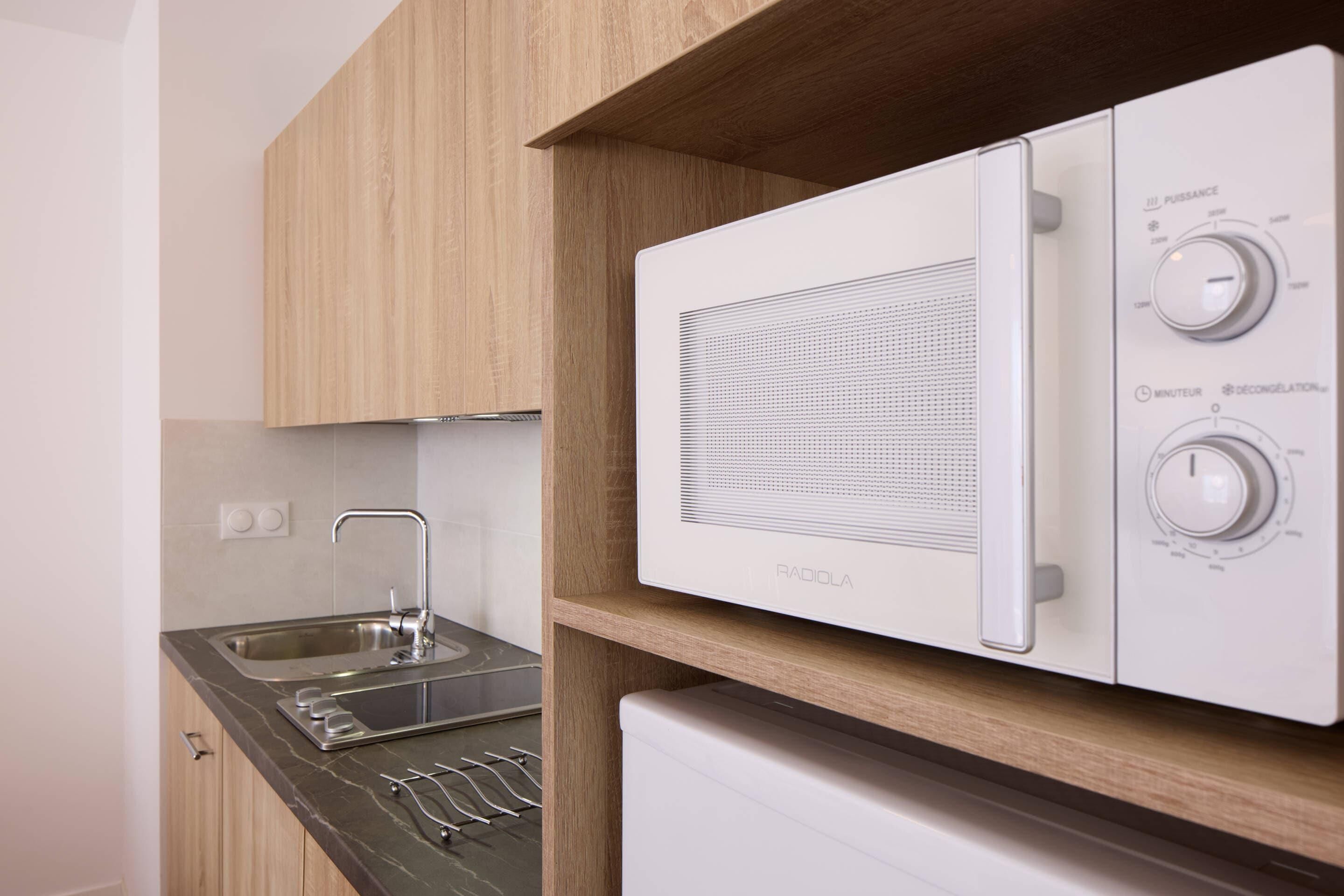 A kitchen with a built-in microwave, a sink, and a stainless steel faucet.
