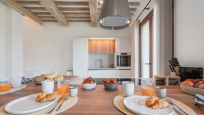 Une cuisine moderne avec des armoires blanches, un four encastré et un luminaire suspendu.