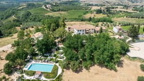 Une villa avec piscine, entourée d’une végétation luxuriante et avec des vignobles en arrière-plan.