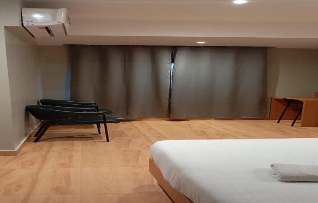 Une chambre d’hôtel avec un lit, une chaise, un bureau et un rideau.