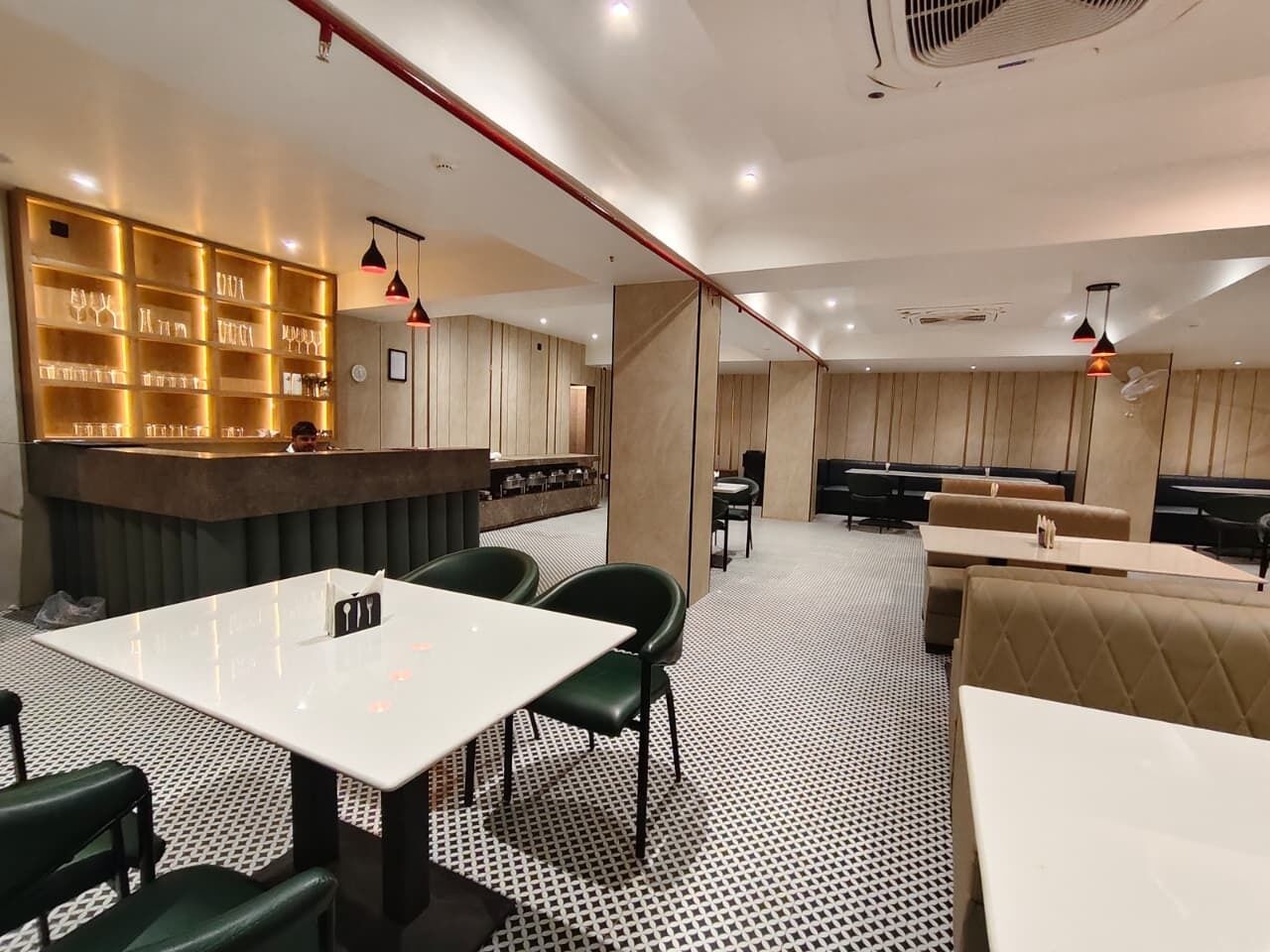Een modern restaurant met een bar, zitplaatsen en een vloer met een patroon.