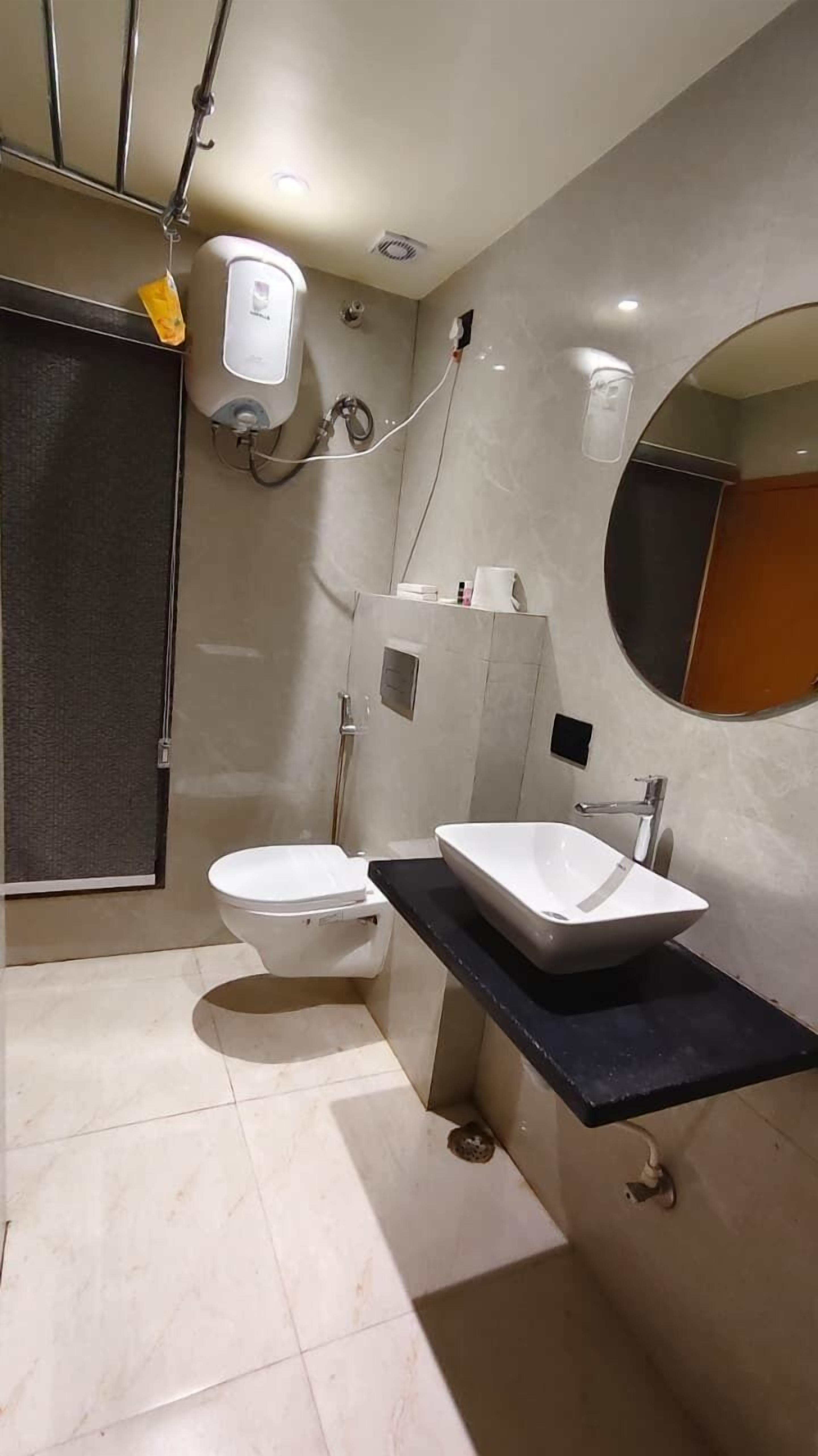 Un baño moderno con inodoro blanco, un lavamanos rectangular grande y un espejo.