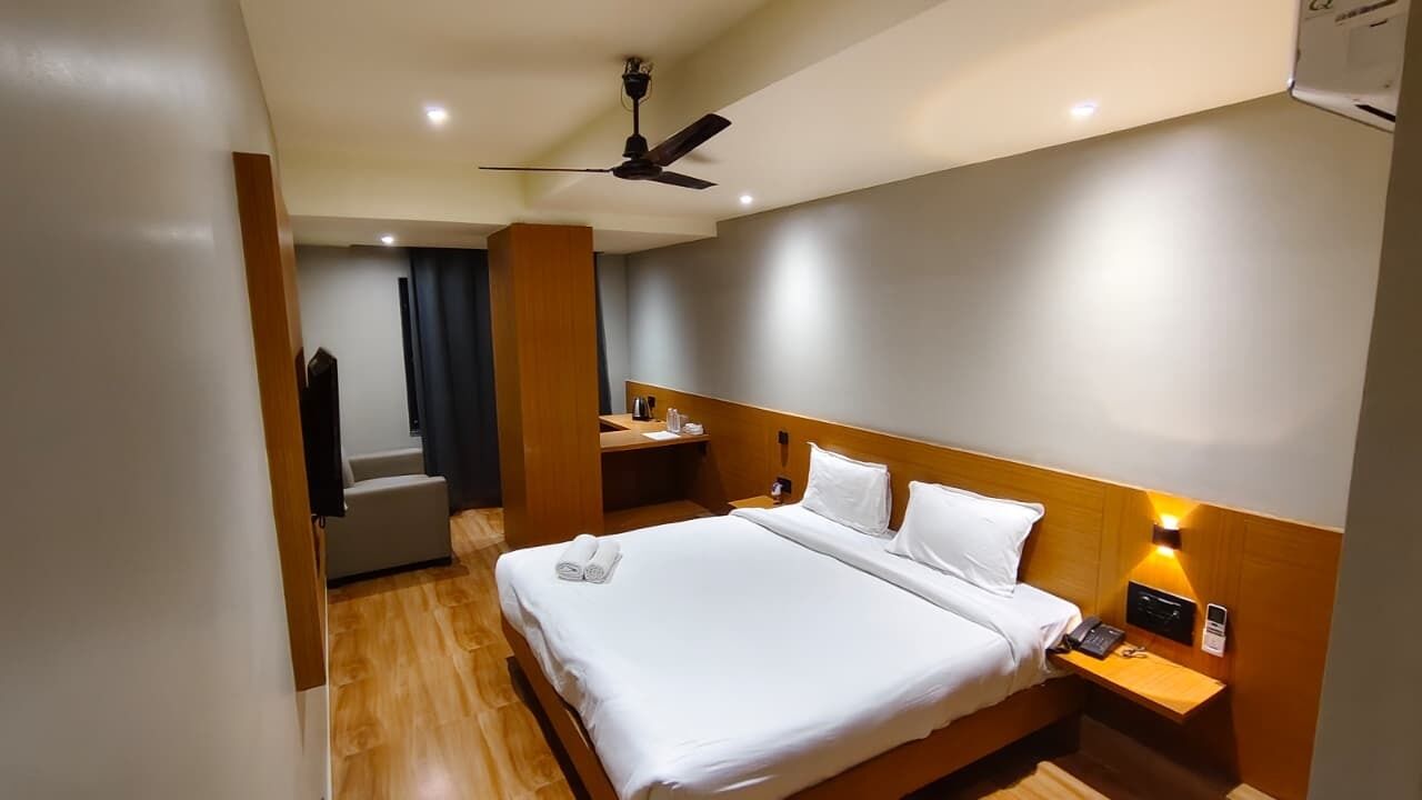 Een hotelkamer met een bed, nachtkastje en plafondventilator.