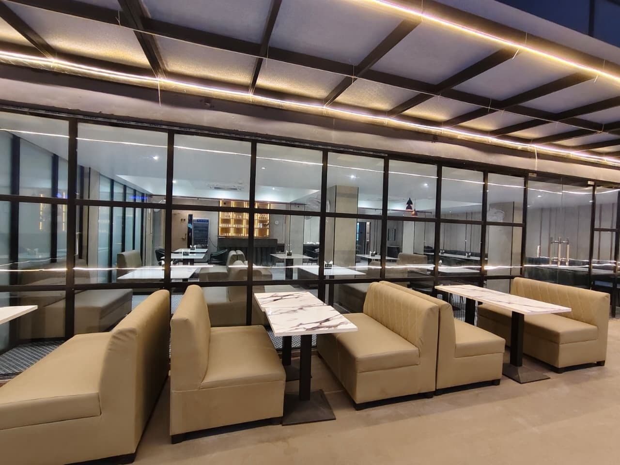 A modern lounge area with glass partitions, leather seating, and a central table.