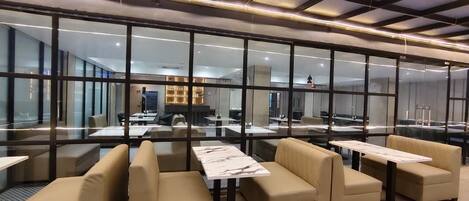 A modern lounge area with glass partitions, leather seating, and a central table.