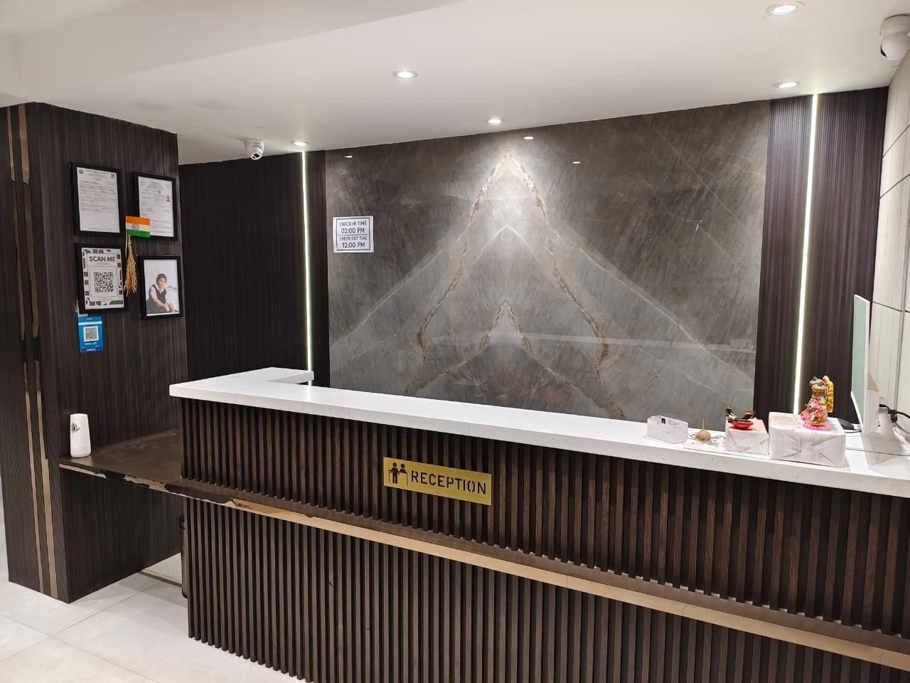 A reception desk with a sign indicating check-in times, a reception area, and a security camera mounted on the wall.