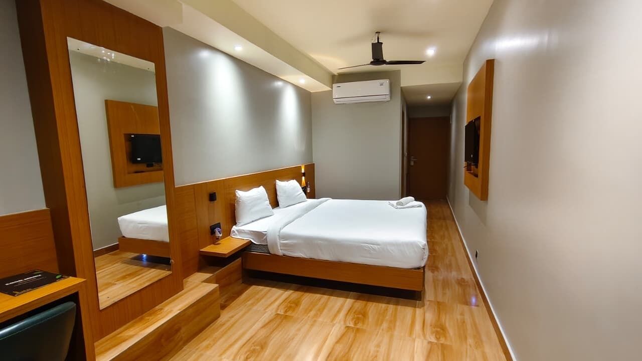 A modern hotel room with a wooden bed, a nightstand, a mirror, and a ceiling fan.