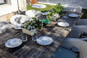 Enjoy a meal al fresco at this charming outdoor dining area, surrounded by lush greenery and comfortable seating.