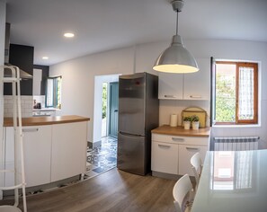 Enjoy cooking in this well-equipped kitchen with a central island, refrigerator, and pendant light.