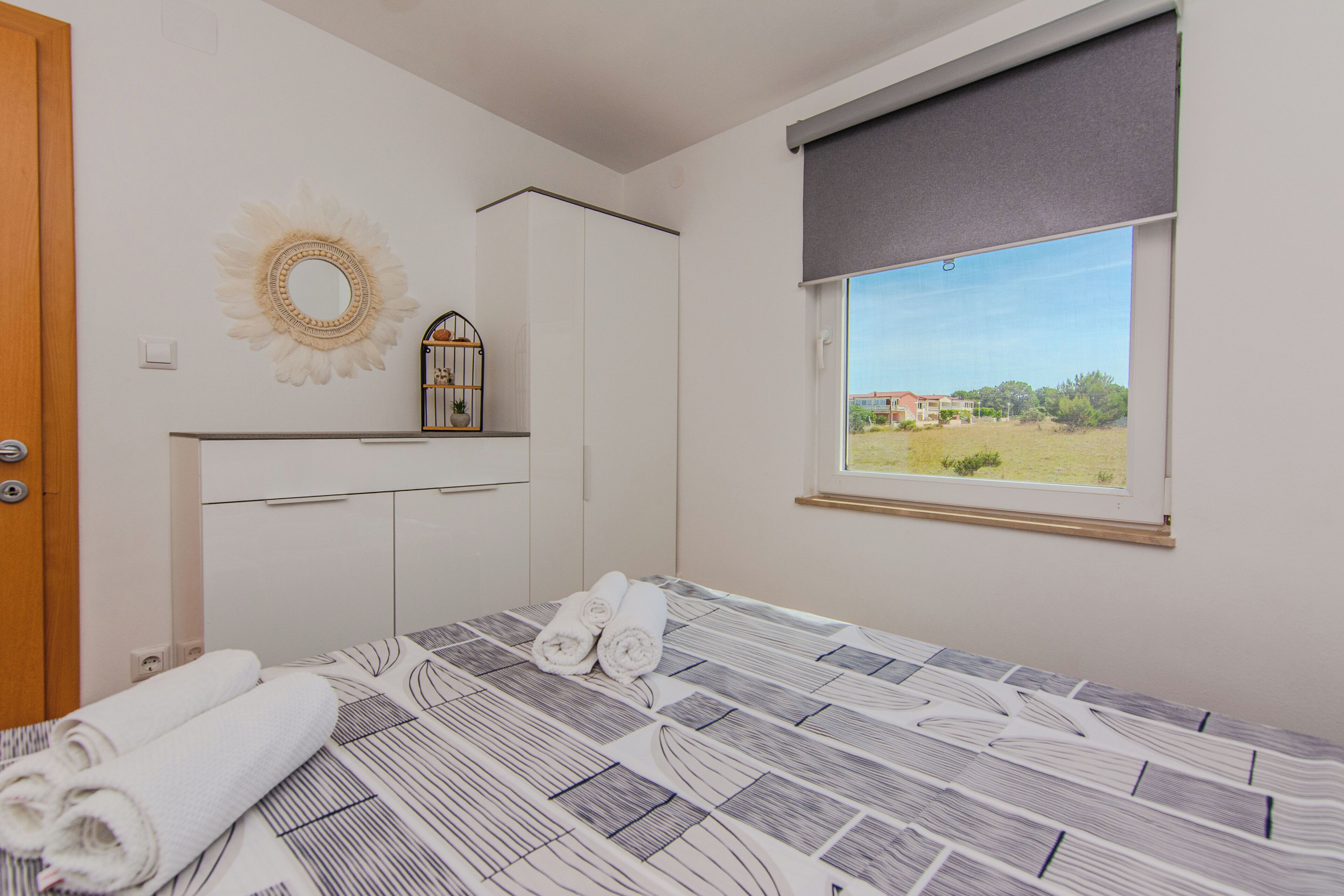 Une chambre à coucher avec un lit, une fenêtre donnant sur un beau paysage, un miroir et une armoire.