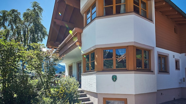 A multi-story building with a white facade and wooden accents, featuring large windows and a balcony. - Chalet Felix by we rent (Saalbach)