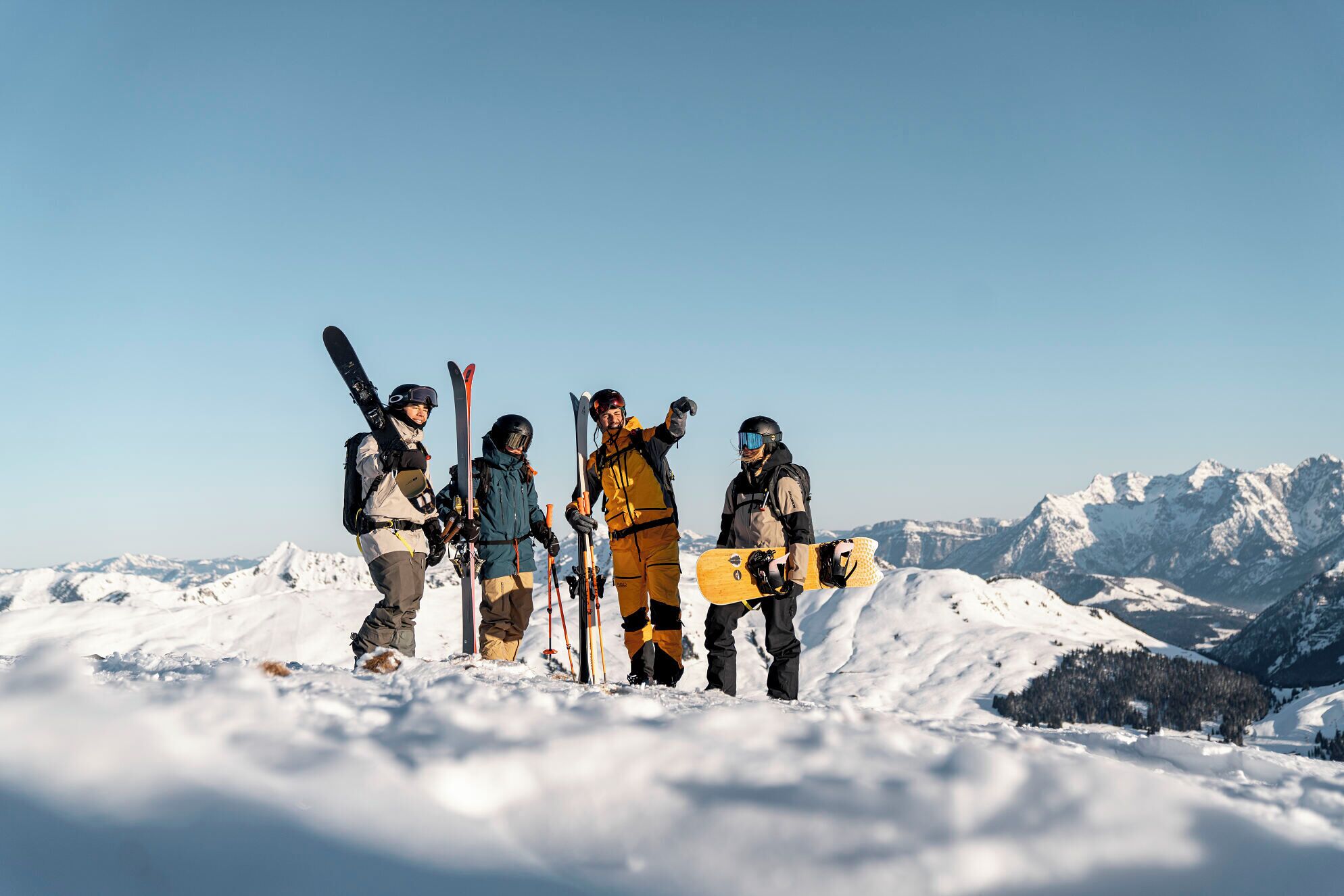 Eine Gruppe von Skifahrern auf einem verschneiten Berg, im Hintergrund schneebedeckte Gipfel.