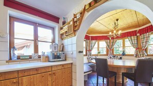 A kitchen with wooden cabinets, a microwave, and a dining area with a bench and chairs. - Chalet Felix by we rent (Saalbach)
