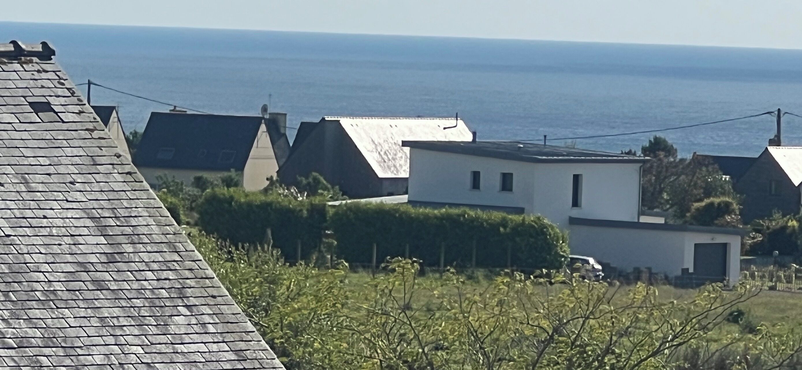 Ein Küstenwohngebiet mit Häusern, freiem Blick auf das Meer und schrägen Dächern.