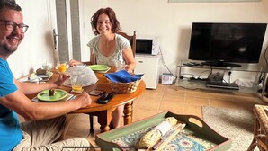 Un comedor con una mesa dispuesta para dos personas, un televisor y un microondas al fondo.