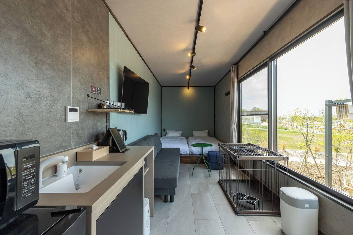 Habitación de hotel moderna con kitchenette, una cama, una mesita y vistas al exterior.