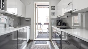 A modern kitchen with stainless steel appliances, a built-in oven, and a large window. - Kotimaailma KotikolmioKauppak saunalla (Lahti)
