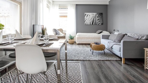 A modern living room with a dining area, grey walls, and a zebra print artwork. - Kotimaailma KotikolmioKauppak saunalla (Lahti)