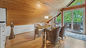 A modern interior with a wooden ceiling, a glass dining table, wicker furniture, and large sliding glass doors. - LAKE Loft Marina (Überlingen)