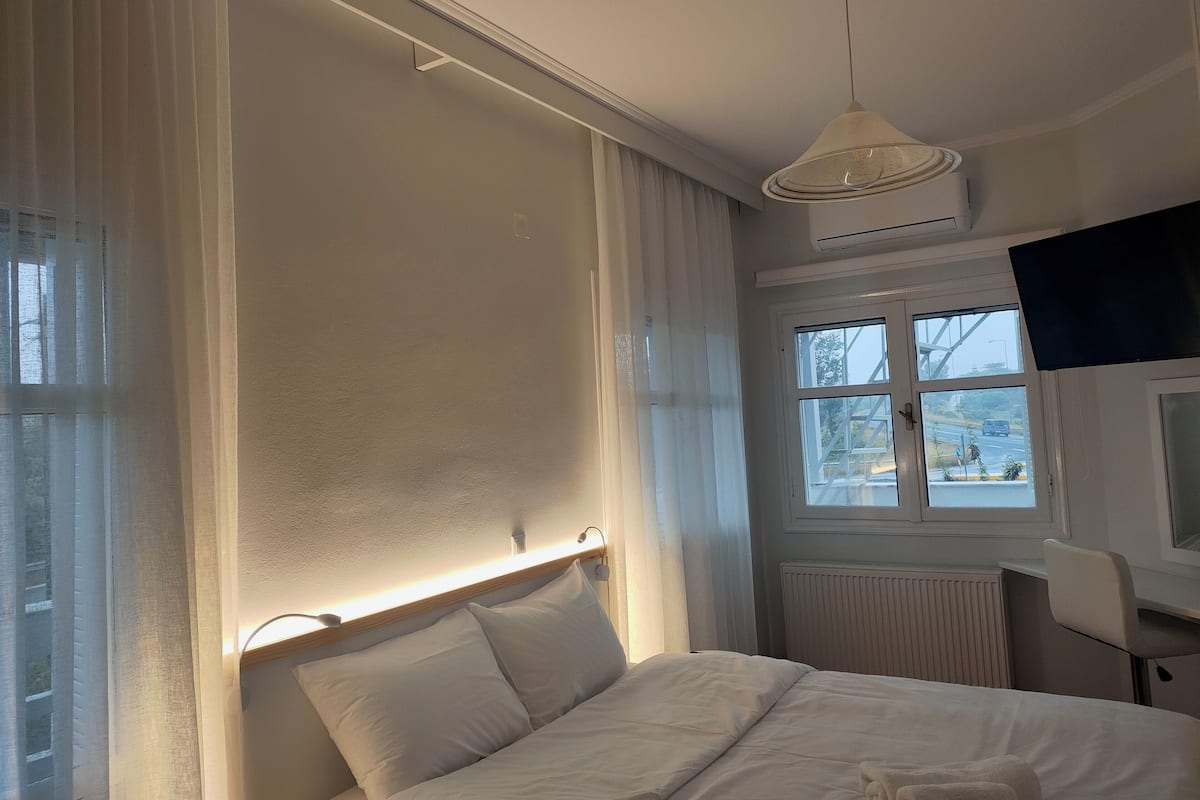 Habitación de hotel con cama, televisión, ventana y vistas al exterior, además de un radiador.