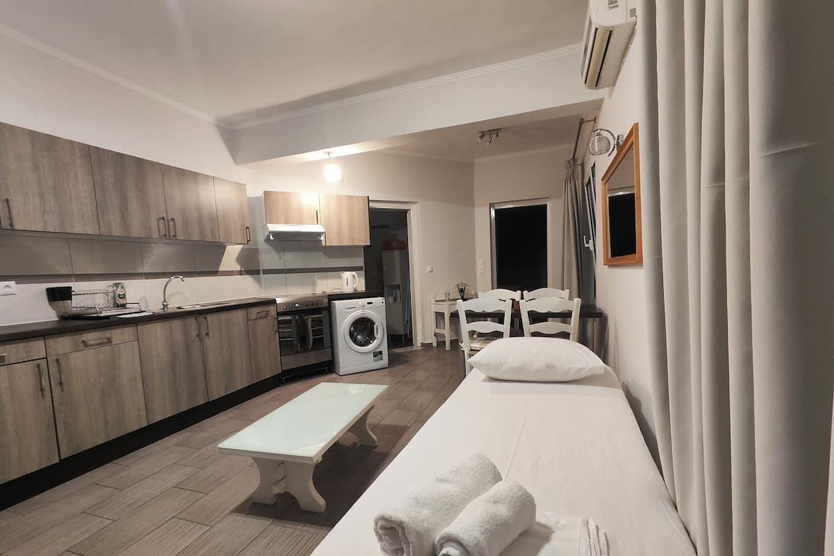 Un espacio habitable funcional con kitchenette, lavadora, zona de comedor y cama con toallas.