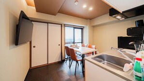 A modern kitchen with a sink, a dining area with chairs, and a television mounted on the wall. - CU Host Dotonbori No.1 Mansion (Osaka)