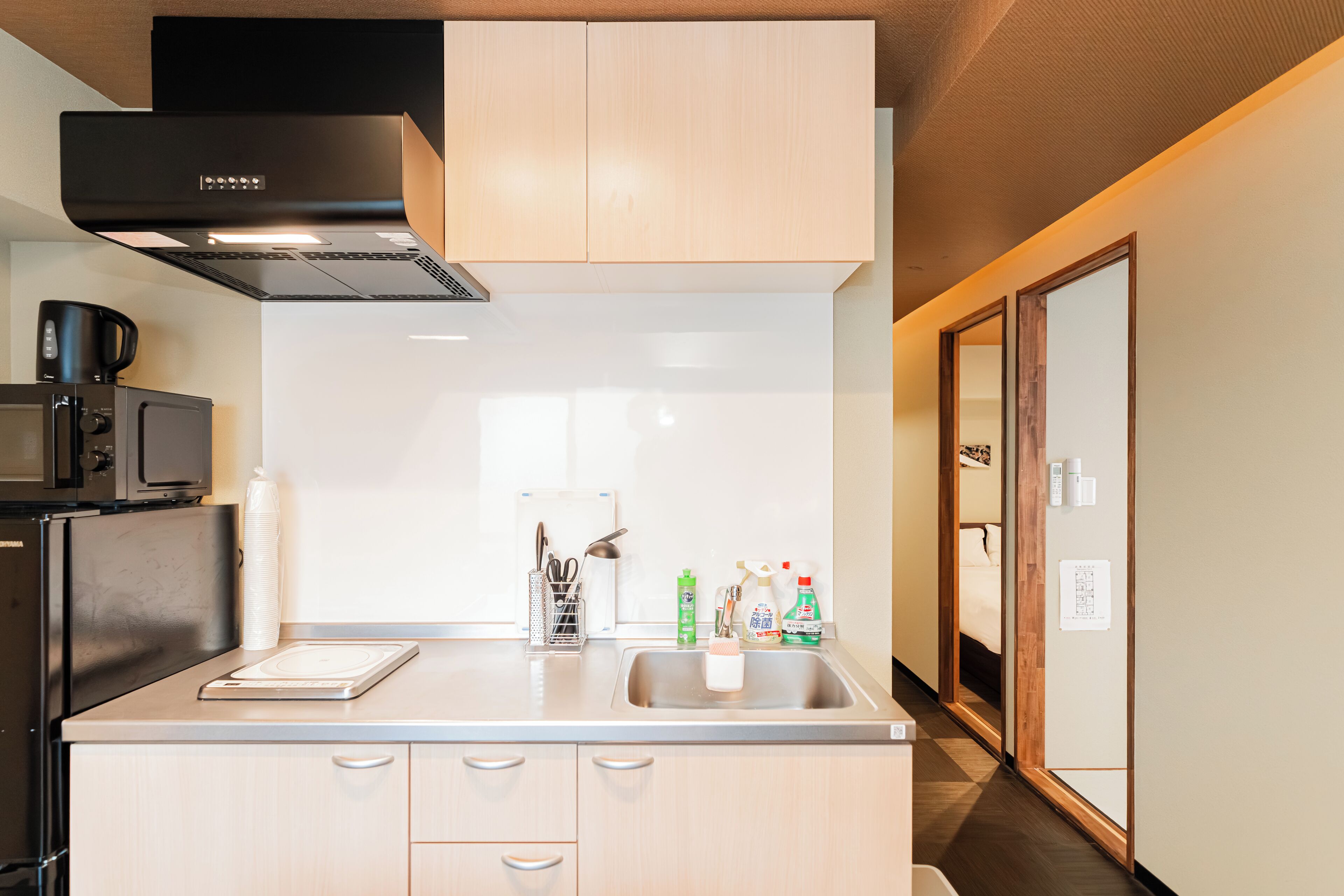 Une cuisine moderne dotée d’un évier en acier inoxydable, d’un four à micro-ondes et d’armoires en bois.