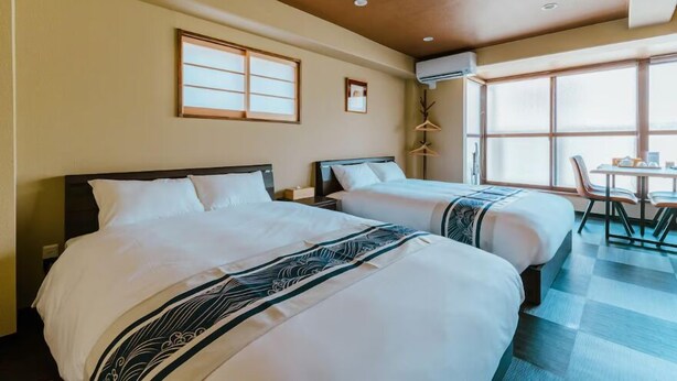 A hotel room with two beds, a dining table, and a window with a view. - CU Host Dotonbori No.1 Mansion (Osaka)