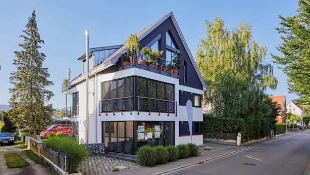 Een modern huis met twee verdiepingen, een balkon, een garage en een oprit.