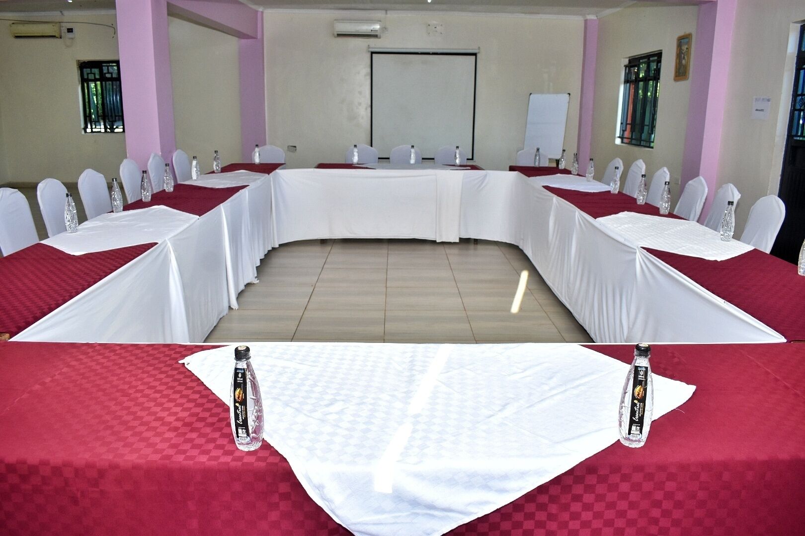 A conference room with a long table, white chairs, and red tablecloths.