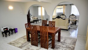A dining area with a wooden table and chairs, a patterned rug, and a sofa in the background. - Elboran Resort and spa (Isiolo)