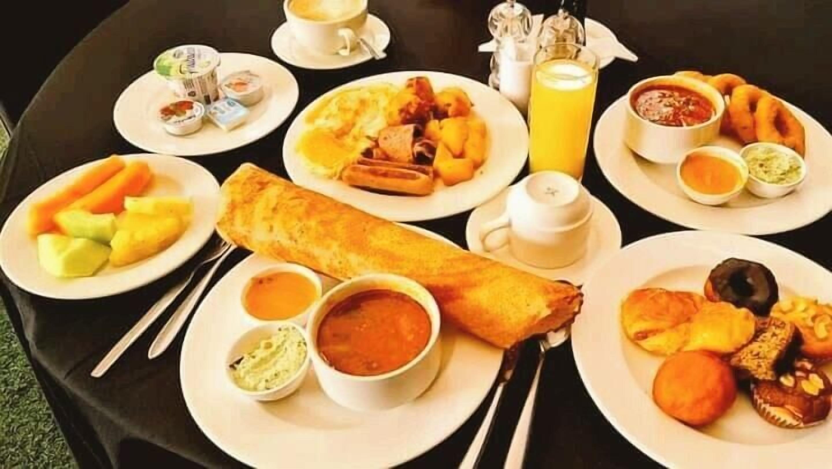 A breakfast spread with various dishes including eggs, toast, fruit, and beverages.