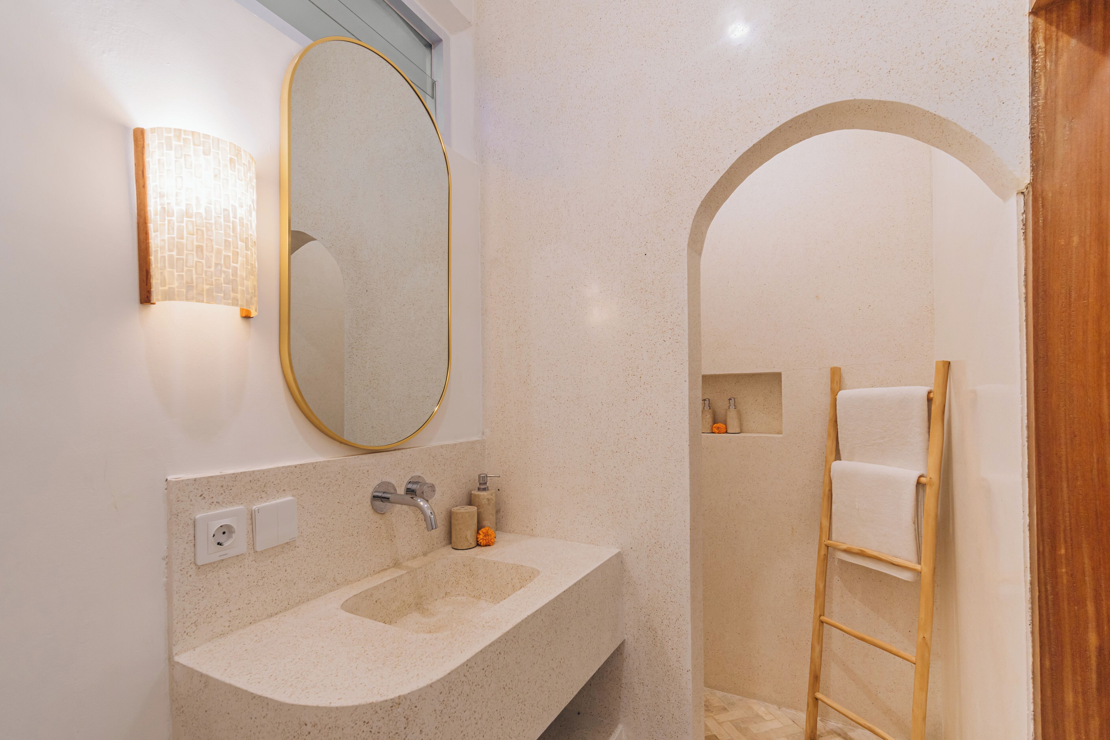 Une salle de bain avec un lavabo sur pied, un miroir avec un cadre doré, un porte-serviettes et un espace douche.
