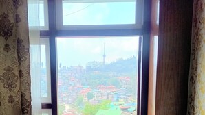 A room with a view of a cityscape through a window. - Kun Dau Residency (Gangtok)
