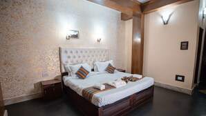 A bedroom with a large bed, wooden headboard, and a patterned wall. - Kun Dau Residency (Gangtok)