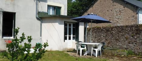 Guests can enjoy a patio with a table and chairs under a shaded area.