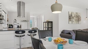 A modern kitchen with a dining area, featuring a central island, bar stools, and a hanging pendant light. - "Agneta" - 1km from the sea by Interhome (Væggerløse)
